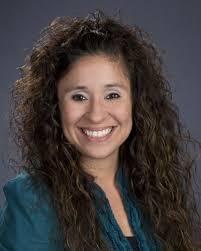 Tracey Flores Headshot with curly hair and a teal shirt