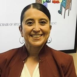 Patricia Candelaria Headshot with brown hair tied back with a brown blazer