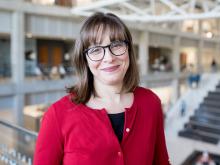 Headshot of Dr. Maura Borrego wearing a red blouse in front of a staircase.