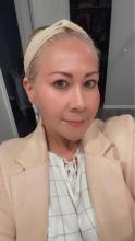 Cristina Santos Headshot with  a blonde hair tied back, a head band and pink cream blazer..