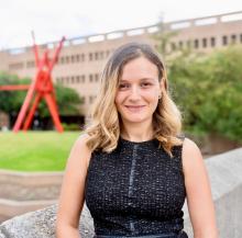 The head and torso of Niveen AbiGhannam, a woman with brown and blonde hair, smiling in a black dress. 