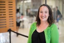 A headshot of Alison Norman, a white woman with dark brown hair, smiling in a green cardigan.
