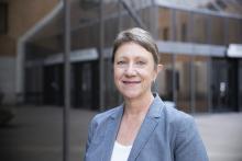 A headshot of Heidi Toprac, a white woman, smiling in a grey blazer and white shirt.