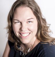 Photo of Amy Kristin Sanders, a white woman with dark wavy hair, smiling and looking at the camera. She is wearing a black shirt and silver necklace.
