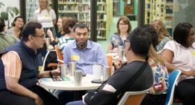 Group of individuals sitting around small tables in discussion