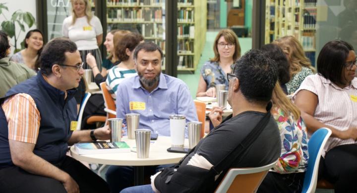 Group of individuals sitting around small tables in discussion
